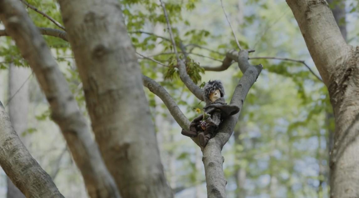 「プックラポッタと森の時間」イメージ画像。木の上に登っている小人（プックラポッタ））