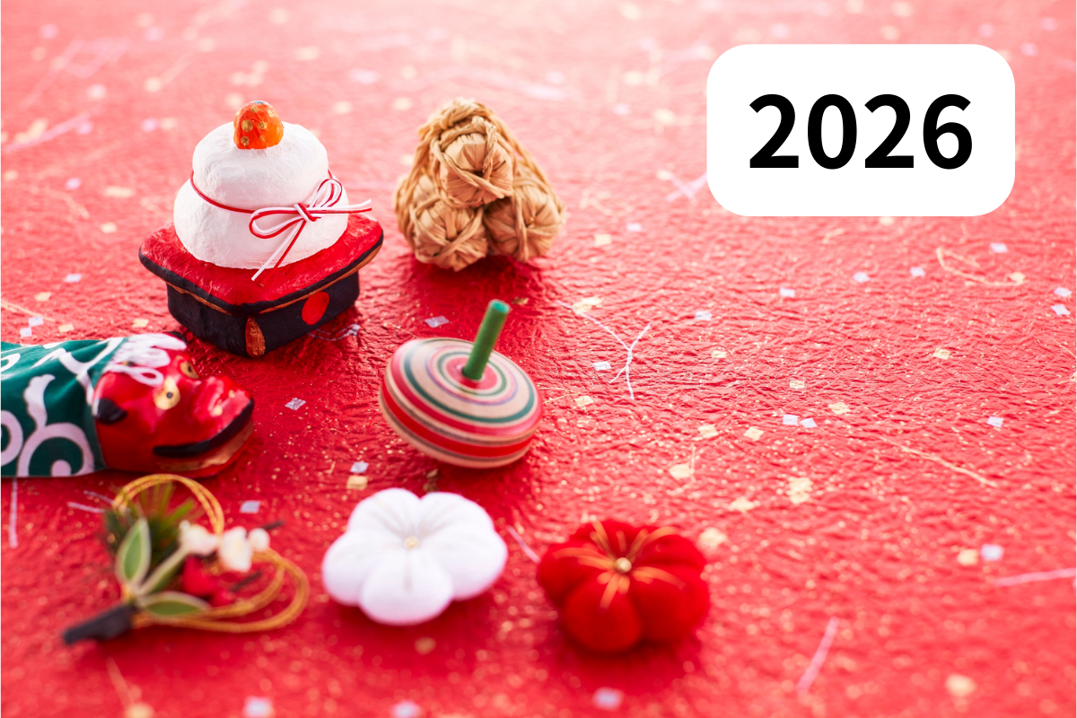 正月のイメージ写真：赤い背景に、2026の文字と米俵、鏡餅、獅子舞、こま、しめ飾り、梅の花が並ぶ。